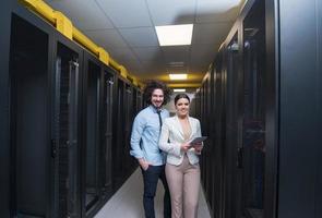 engineer showing working data center server room to female chief photo