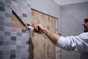 worker remove demolish old tiles in a bathroom photo