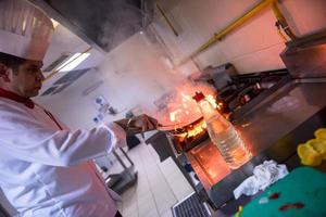 chef haciendo flambeado en la comida foto