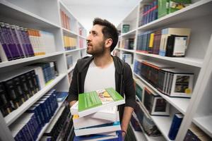 Student holding lot of books in school library photo