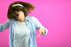 mujer morena con gafas negras bailando y escuchando música aislada de fondo rosa foto