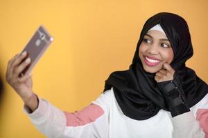 mujer musulmana africana con una hermosa sonrisa se toma un selfie con un teléfono celular foto