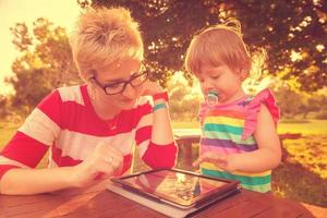 mom and her little daughter using tablet computer photo