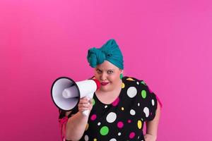 Funny plus size woman woman girl posing isolated on pastel pink wall background studio portrait. People sincere emotions lifestyle concept. Mock up copy space. Screaming in megaphone. photo