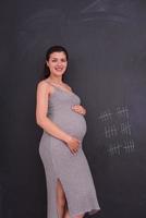 Portrait of pregnant woman in front of black chalkboard photo