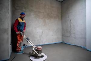 worker performing and polishing sand and cement screed floor photo