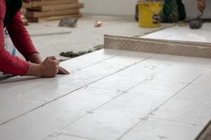 worker installing the ceramic wood effect tiles on the floor photo