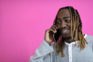 afro guy uses a phone while posing in front of a pink background. photo