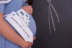 Portrait of pregnant woman in front of black chalkboard photo