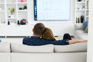 young couple watching tv at home in bright living room photo