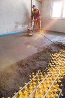 worker performing and polishing sand and cement screed floor photo