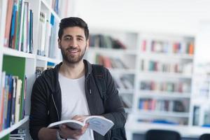 portrait of student while reading book  in school library photo
