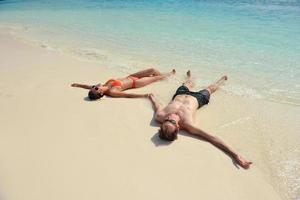 feliz pareja joven divertirse en la playa foto