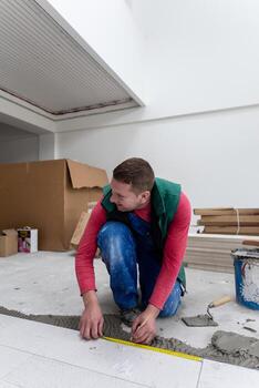 worker installing the ceramic wood effect tiles on the floor photo