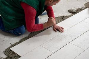 worker installing the ceramic wood effect tiles on the floor photo