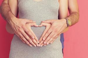 pregnant  couple showing heart with their hands photo