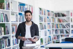 portrait of student while reading book  in school library photo