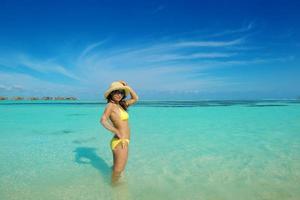 mujer asiática descansando sobre la arena en la playa foto