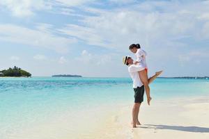 feliz pareja joven divertirse en la playa foto