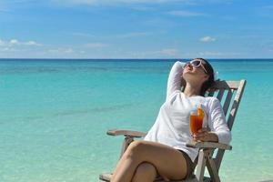 Beautiful young woman with a drink by the sea photo