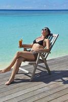 Beautiful young woman with a drink by the sea photo