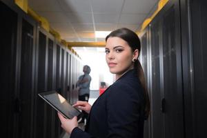 Female engineer working on a tablet computer in server room photo