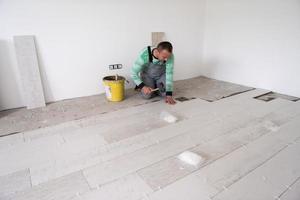 worker installing the ceramic wood effect tiles on the floor photo