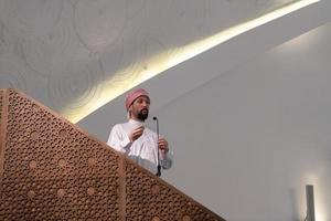 el joven imán árabe musulmán tiene un discurso en la oración del viernes por la tarde en la mezquita. foto