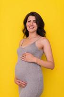 Portrait of pregnant woman over yellow background photo