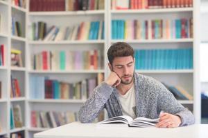 portrait of student while reading book  in school library photo