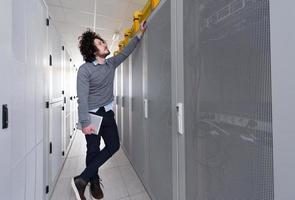 IT engineer working on a tablet computer in server room photo