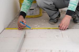 worker installing the ceramic wood effect tiles on the floor photo