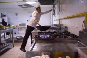 chef preparando comida, friendo en sartén wok foto