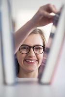 portrait of famale student selecting book to read in library photo