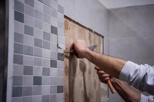 trabajador quitar demoler azulejos viejos en un baño foto