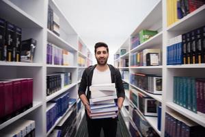 Student holding lot of books in school library photo