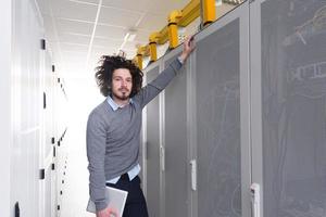 IT engineer working on a tablet computer in server room photo