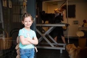 little cute girl standing in front of beauty salon for animals photo