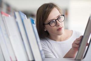 portrait of famale student selecting book to read in library photo