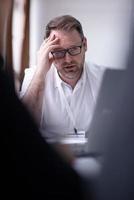 Business man writing notes while working on laptop photo