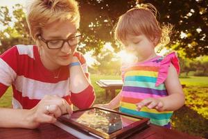 mom and her little daughter using tablet computer photo