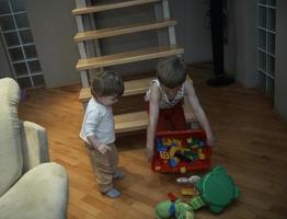 niño pequeño jugando y llevándole juguetes a su hermana foto