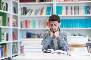 portrait of student while reading book  in school library photo