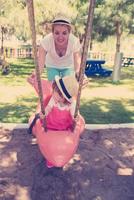 mother and daughter swinging in the park photo