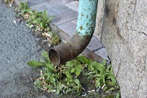 An iron spillway pipe sticking out of the house. Sewer pipe. photo