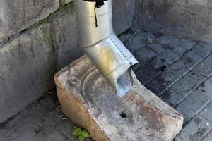 An iron spillway pipe sticking out of the house. Sewer pipe. photo