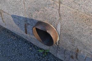 An iron spillway pipe sticking out of the house. Sewer pipe. photo