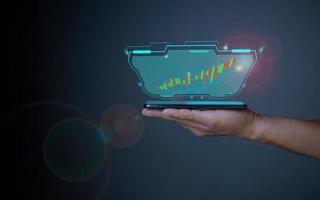 Hologram image of a candlestick chart from a phone on a person's hand. Offer trading, investment ideas photo
