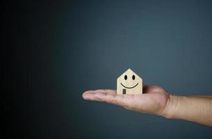 Happy house concept. Hand holding a smiling model house. Indicates happiness and love in the house. photo