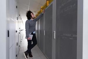 IT engineer working on a tablet computer in server room photo